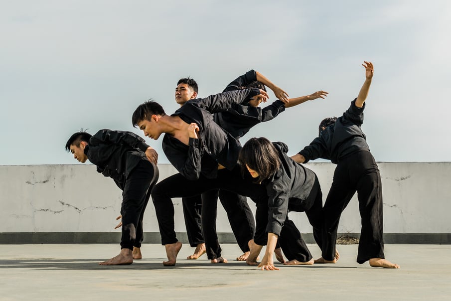 Six People in Black Matching Clothes Dancing at Daytime